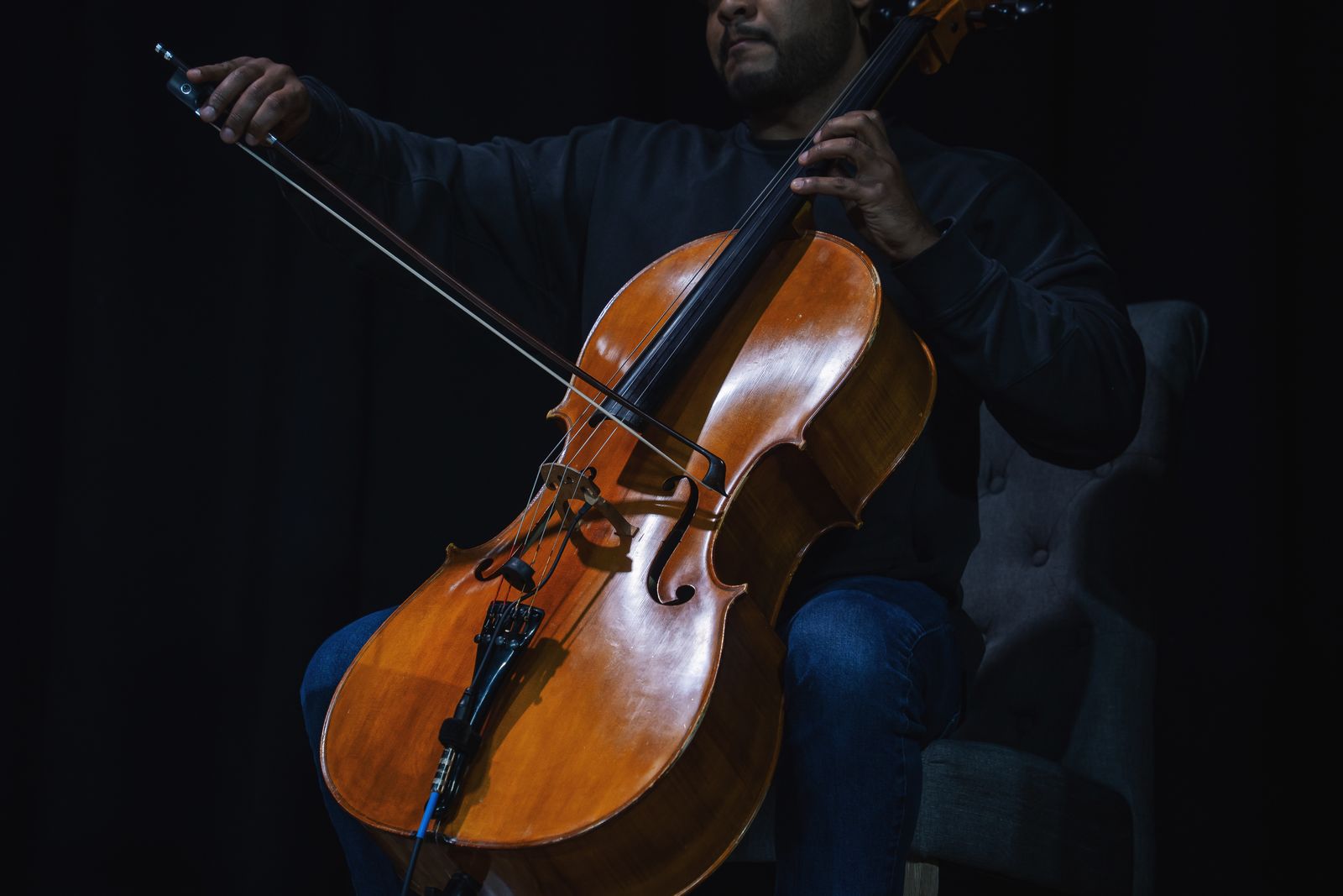 A cellist playing on a darkened stage